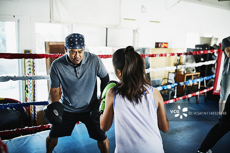 在拳击场上与年轻女拳击手一起训练的拳击教练图片素材
