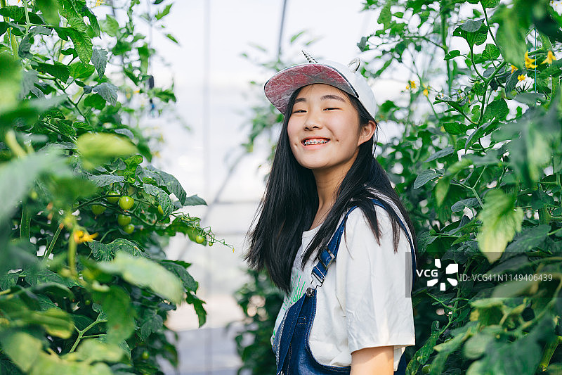 亚洲少女收获新鲜蔬菜，并看着镜头从农场快乐图片素材