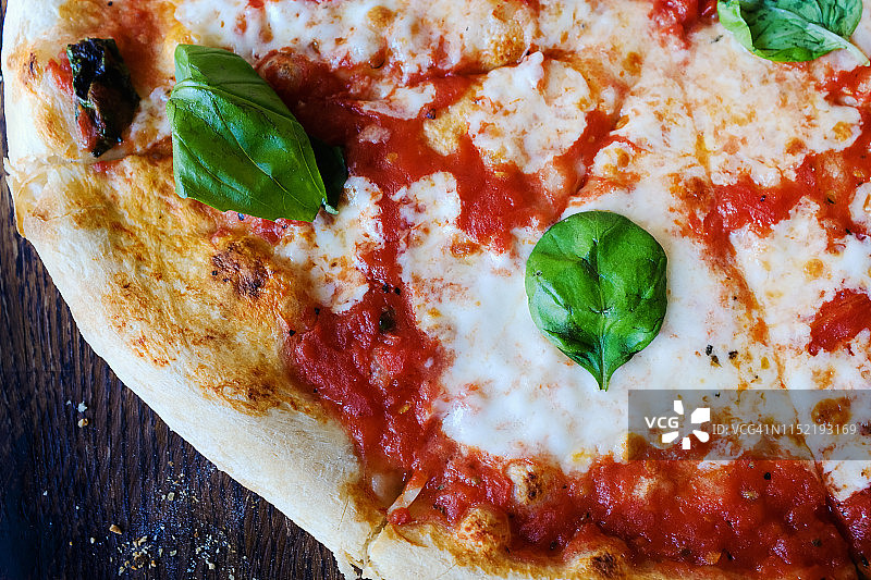 素菜披萨，配上马苏里拉芝士、番茄、香料和新鲜罗勒。美味的意大利比萨。切成薄片的玛格丽塔披萨放在木板上。近距离图片素材