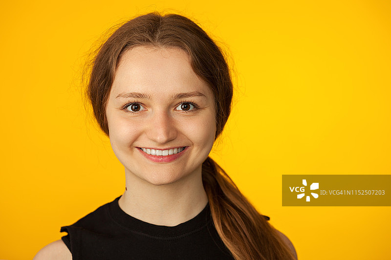 一个迷人的18岁女人在黄色背景的工作室肖像图片素材