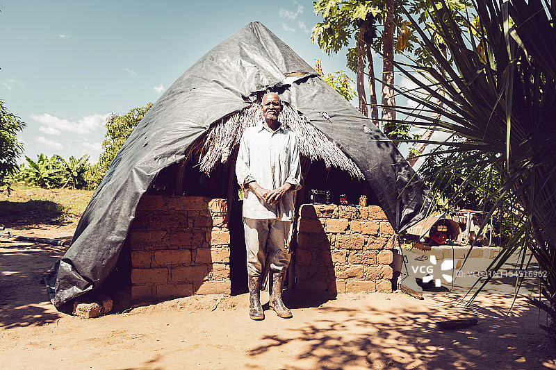 一个非洲农民站在他的小屋前图片素材