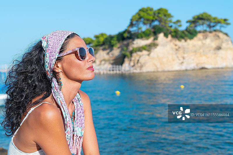 中年妇女戴着太阳镜在兹金索斯避暑，身后是大海图片素材