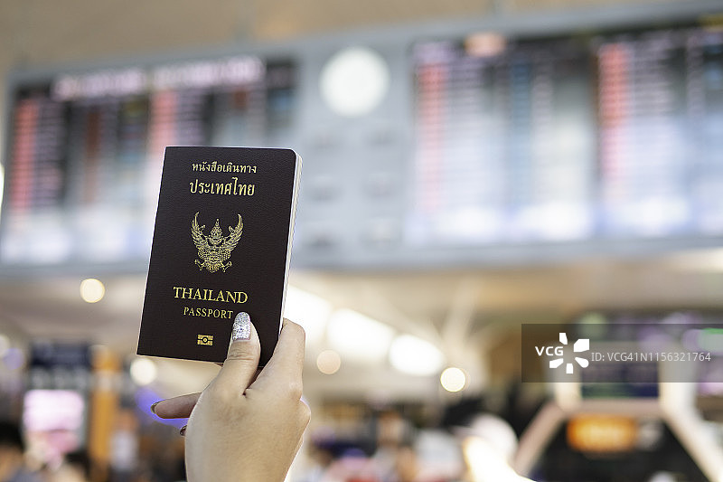 旅游和假日概念。在机场拿着泰国护照和航班时刻表图片素材