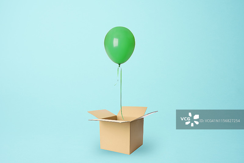 一个绿色的气球从纸板箱里飘出来图片素材
