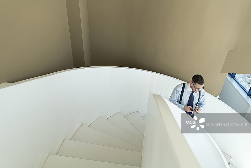 商人在现代办公室的楼梯上使用手机图片素材
