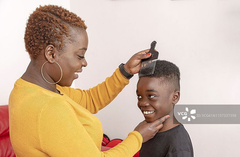 安多弗，汉普郡，英国，英国，9岁的卷发小男孩，他的妈妈用一个宽齿非洲式梳头给他梳头。图片素材