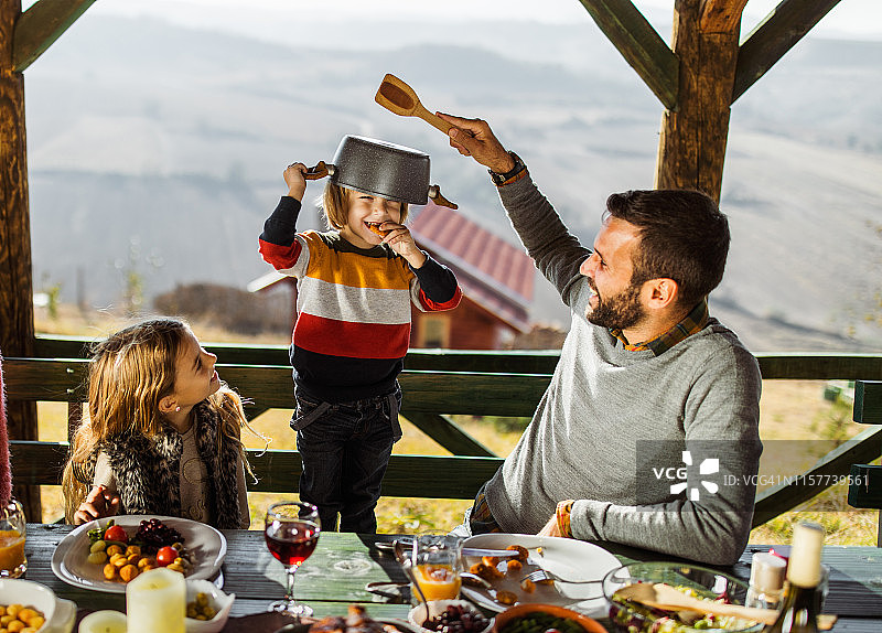 快乐的单身父亲在阳台上和孩子们吃午饭。图片素材