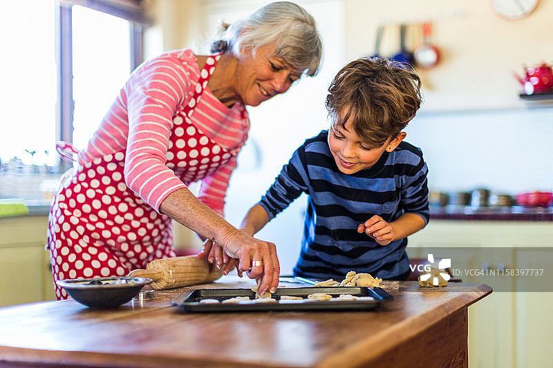 奶奶在厨房里帮孙子烤饼干图片素材
