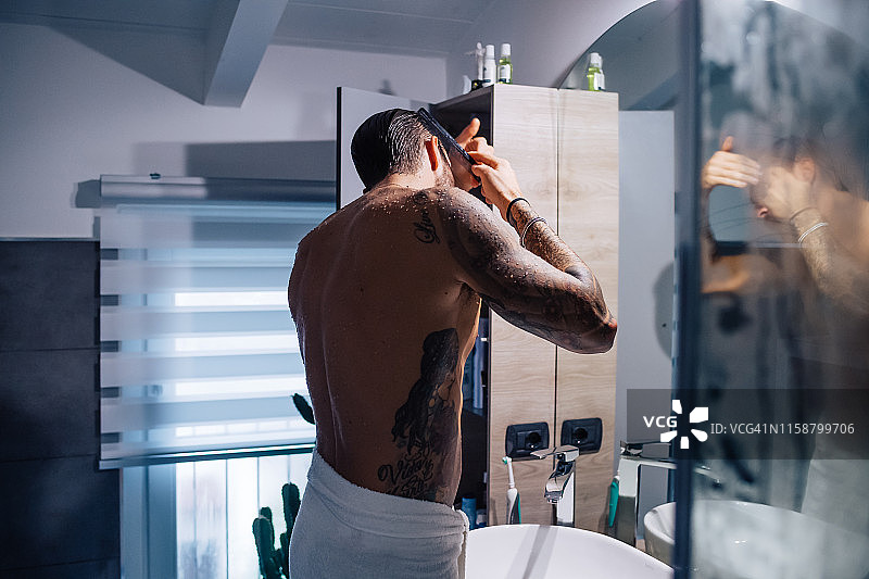 有纹身的中年男子在浴室镜子前梳头发图片素材