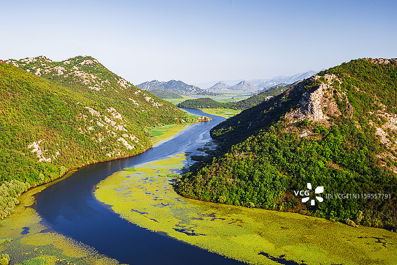 夏天的景观河与明亮的黄色睡莲叶被山包围图片素材