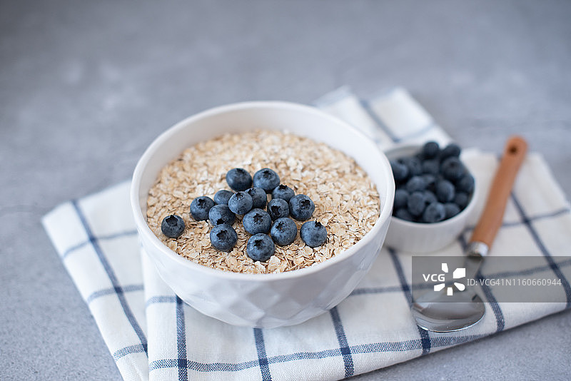 在灰色混凝土背景的碗里自制的蓝莓和草莓燕麦粥。健康的早餐。图片素材