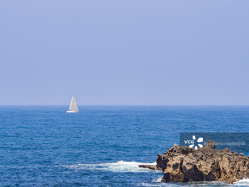 在坎塔布里亚(西班牙)，一艘船在地平线上航行的海岸景观图片素材