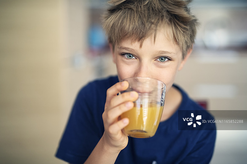 可爱的小男孩喝着一杯橙汁图片素材