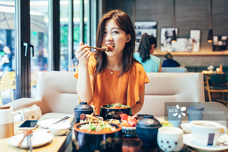年轻的亚洲女人喜欢日本食物鳗鱼米饭。图片素材