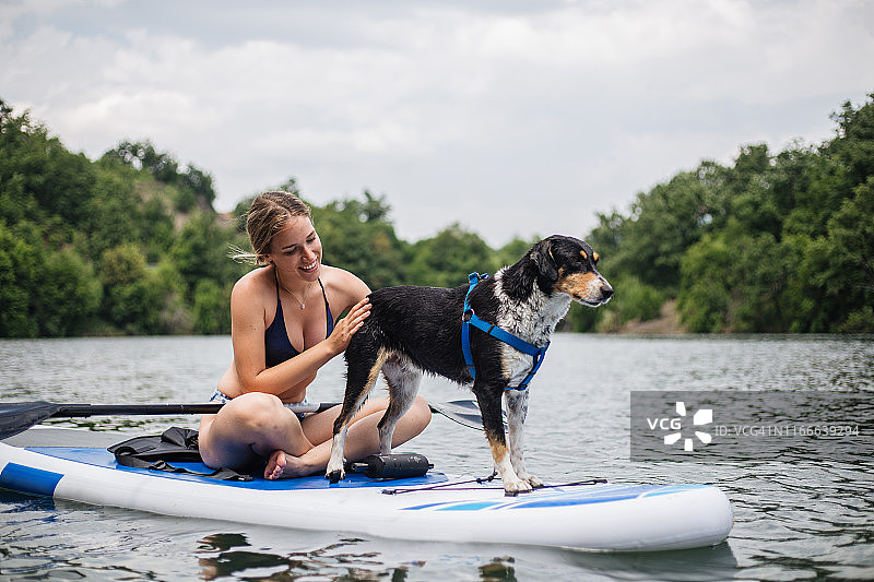 一个女人和她的狗在湖边放松图片素材