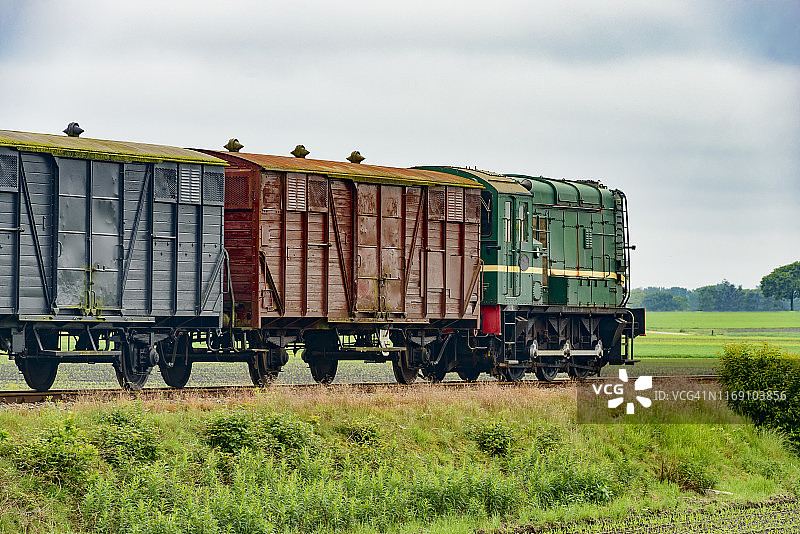 旧的柴油货车牵引着农村的各种火车车厢。图片素材