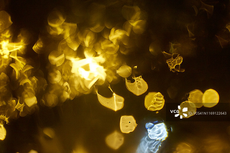 抽象的黄色模糊光与雨在明镜上图片素材