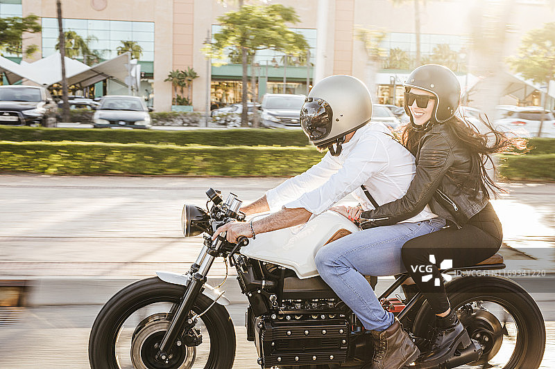 一对夫妇在城市里骑摩托车图片素材