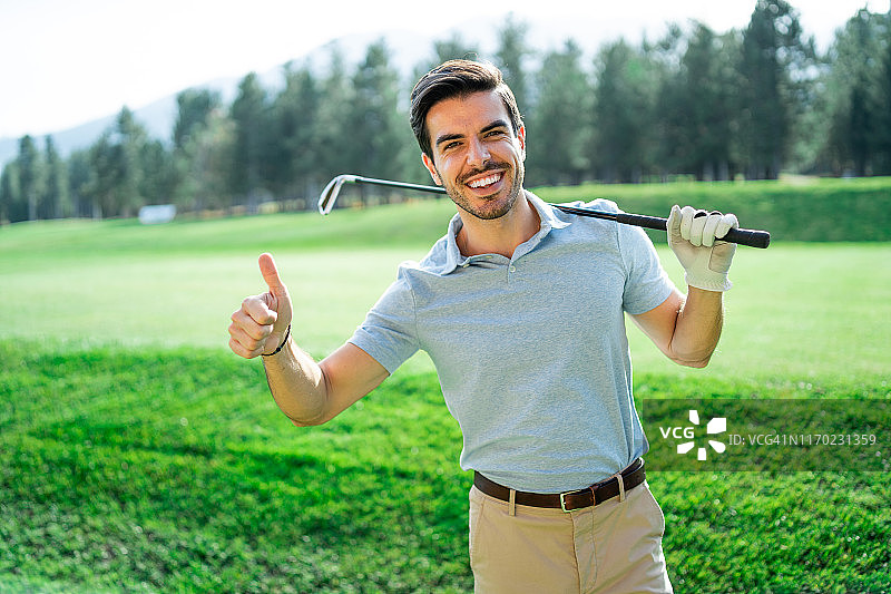 男高尔夫球手站在高尔夫球场上，竖起大拇指图片素材