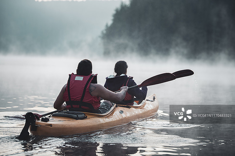 年轻夫妇在山湖皮划艇冒险。图片素材