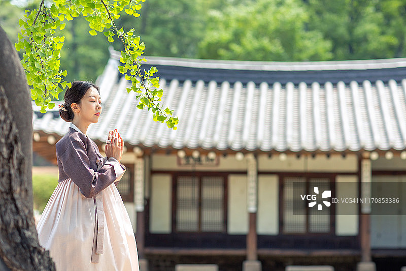 身着韩服的女子站在韩国传统民居前图片素材