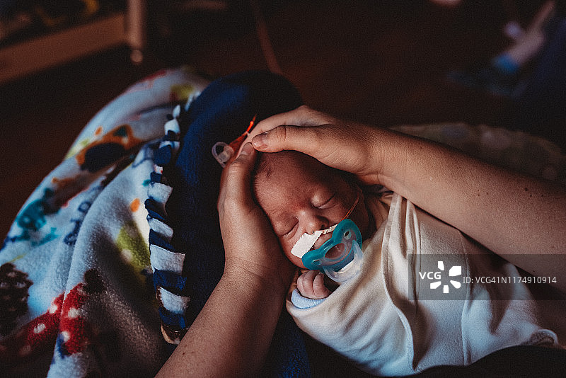 29周早产儿握着母亲的手，在新生儿重症监护室被抱着图片素材