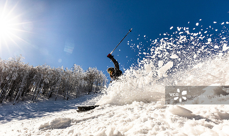 一个女人在山上滑雪溅雪的全景。图片素材