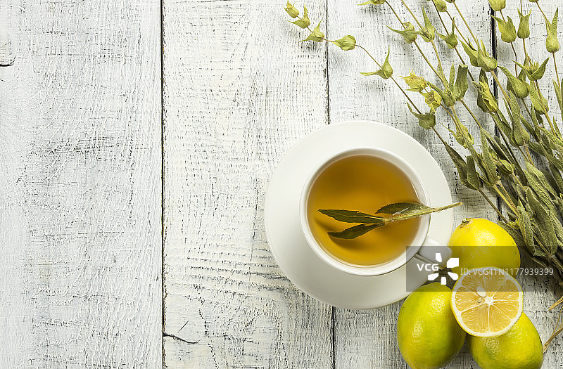 白色杯草药鼠尾草茶与干鼠尾草叶子和柠檬在白色木制乡村背景。凉茶概念热饮，丹参图片素材