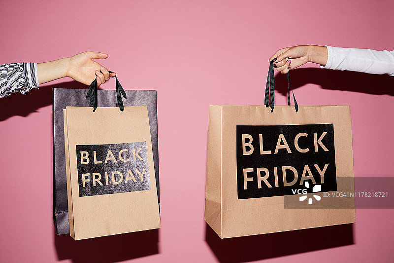 背景图像，不认识的女士拿着纸袋与黑色星期五的文字，购物概念图片素材