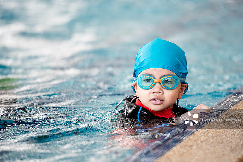 一个女孩穿着衣服练习游泳。图片素材