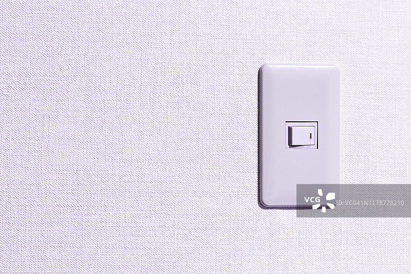 简单的电灯开关安装在白色的墙壁上。图片素材