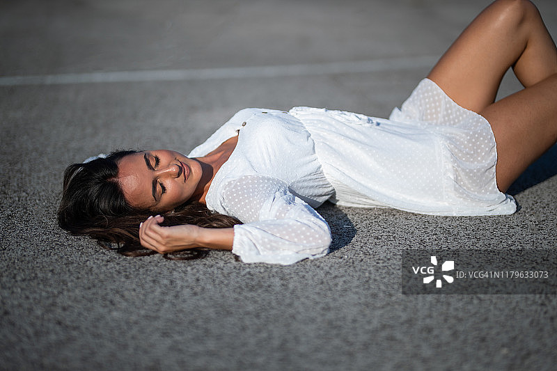 一个年轻女子躺在户外的篮球场上图片素材
