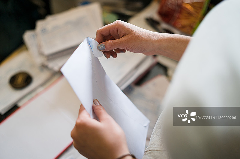 靠近女孩女性女人手握和打开白色信封在办公室工作或在家里与账单邮件或保险合同发票信图片素材