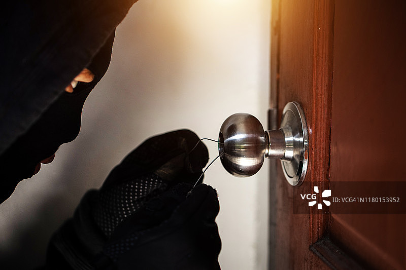 一个危险的窃贼带着钥匙闯进了受害者的门，小偷们图片素材