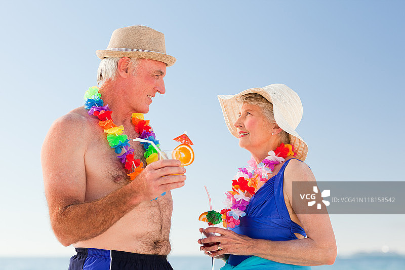 老夫妇在海滩上喝鸡尾酒图片素材