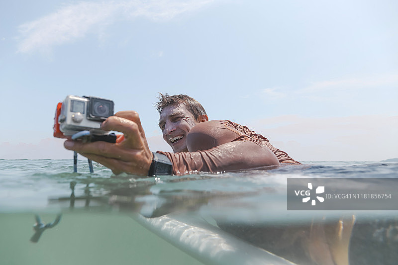 冲浪者带着摄像机躺在冲浪板上图片素材