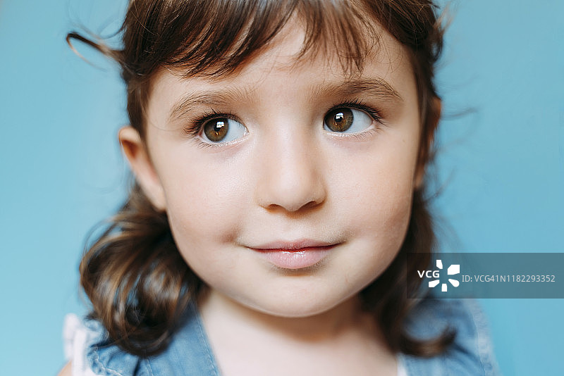 可爱的小女孩的肖像，蓝色的背景图片素材