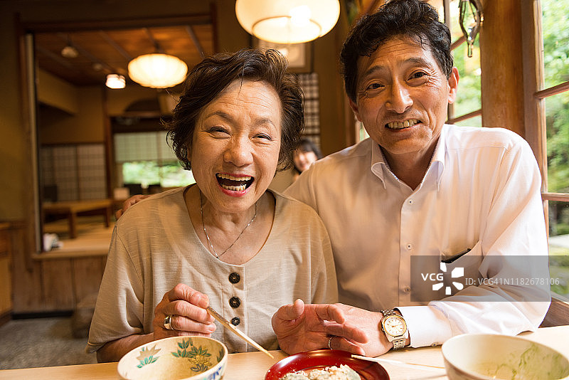 快乐成熟的日本夫妇在餐厅吃饭看着镜头图片素材