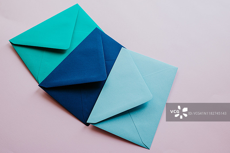 浅色背景上的彩色纸信封。新邮件，写消息。收发信件。邮政递送服务。空白的信封，空白的空间。人沟通,文书工作。信封特写镜头图片素材