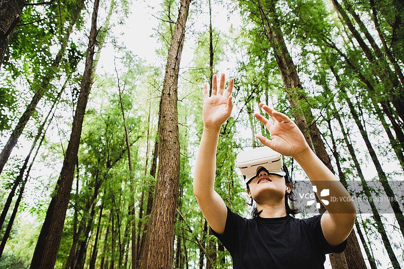 一个女人在森林中使用虚拟现实头盔图片素材