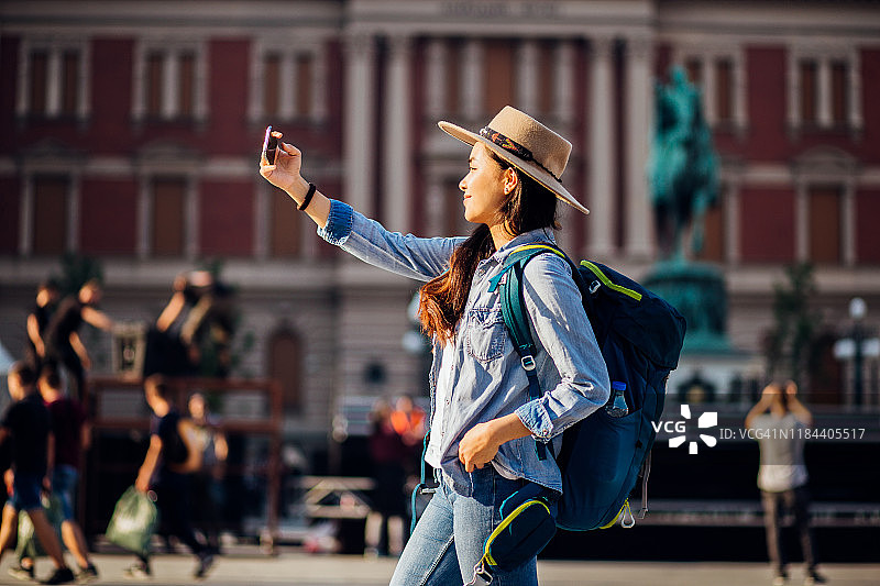 美丽的亚洲游客用她的智能手机拍照图片素材