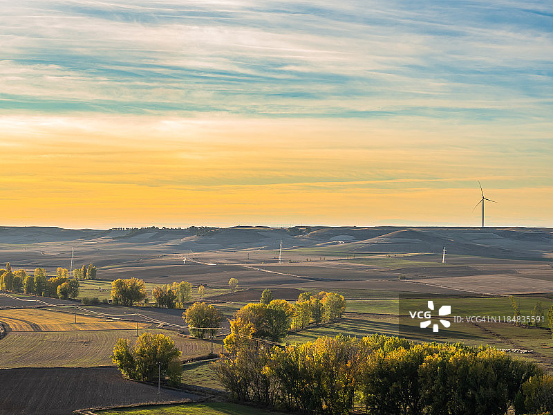 鸟瞰图一个风景优美的秋天景观日落与农田，农村道路，房屋和风力涡轮机在地平线上在西班牙市政Torrelobatón。图片素材