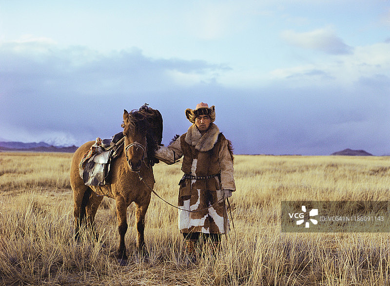 蒙古草原上骑着马的猎鹰人的肖像图片素材