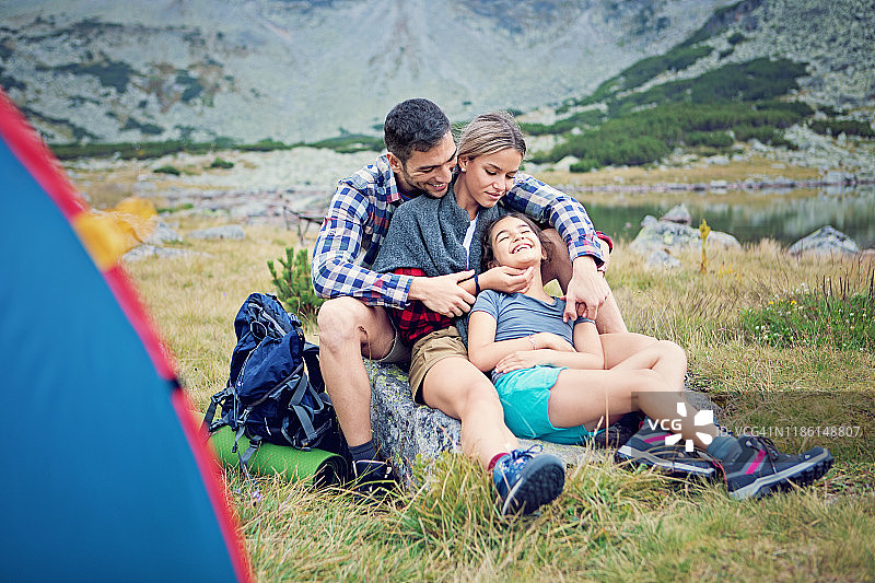 快乐的徒步旅行家庭在山上的湖边放松和拥抱图片素材