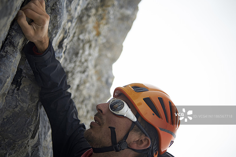 在晴朗的天空下，登山者戴着头盔爬山图片素材