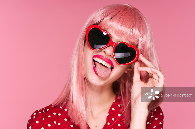 有趣的女人在眼镜心在波尔卡点连衣裙粉红色的背景图片素材