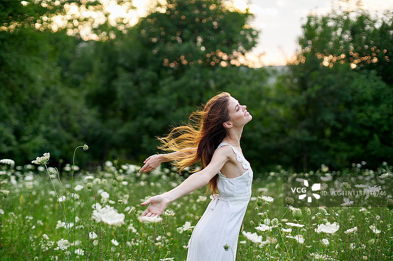美丽的年轻女孩跑在一个白色的裙子在田野与鲜花的自然图片素材