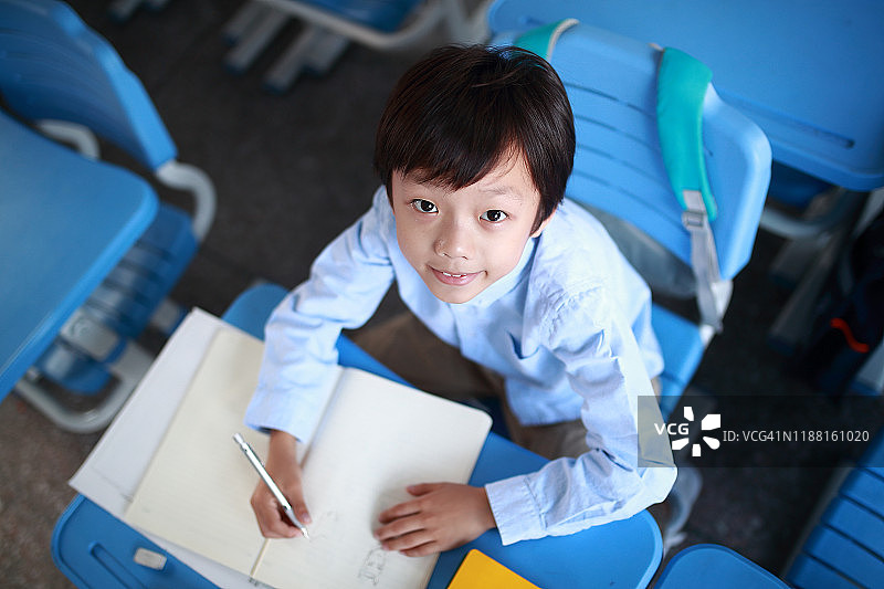 小男孩在教室里的书桌前读书图片素材