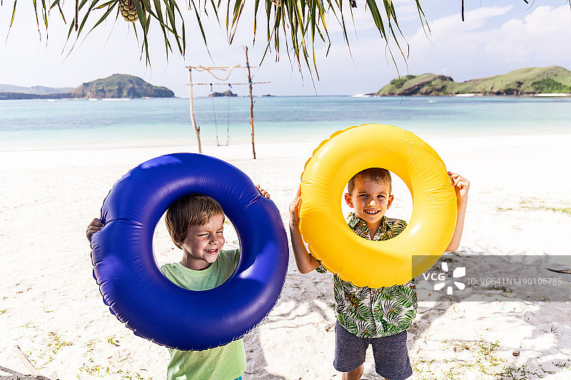 可爱快乐的男孩在海滩上玩充气环。图片素材