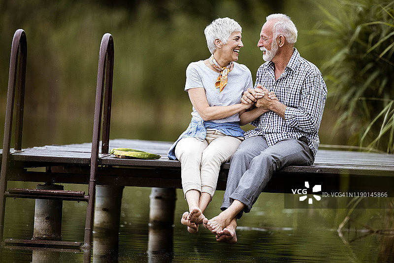 一对相爱的老夫妇在码头上放松聊天。图片素材